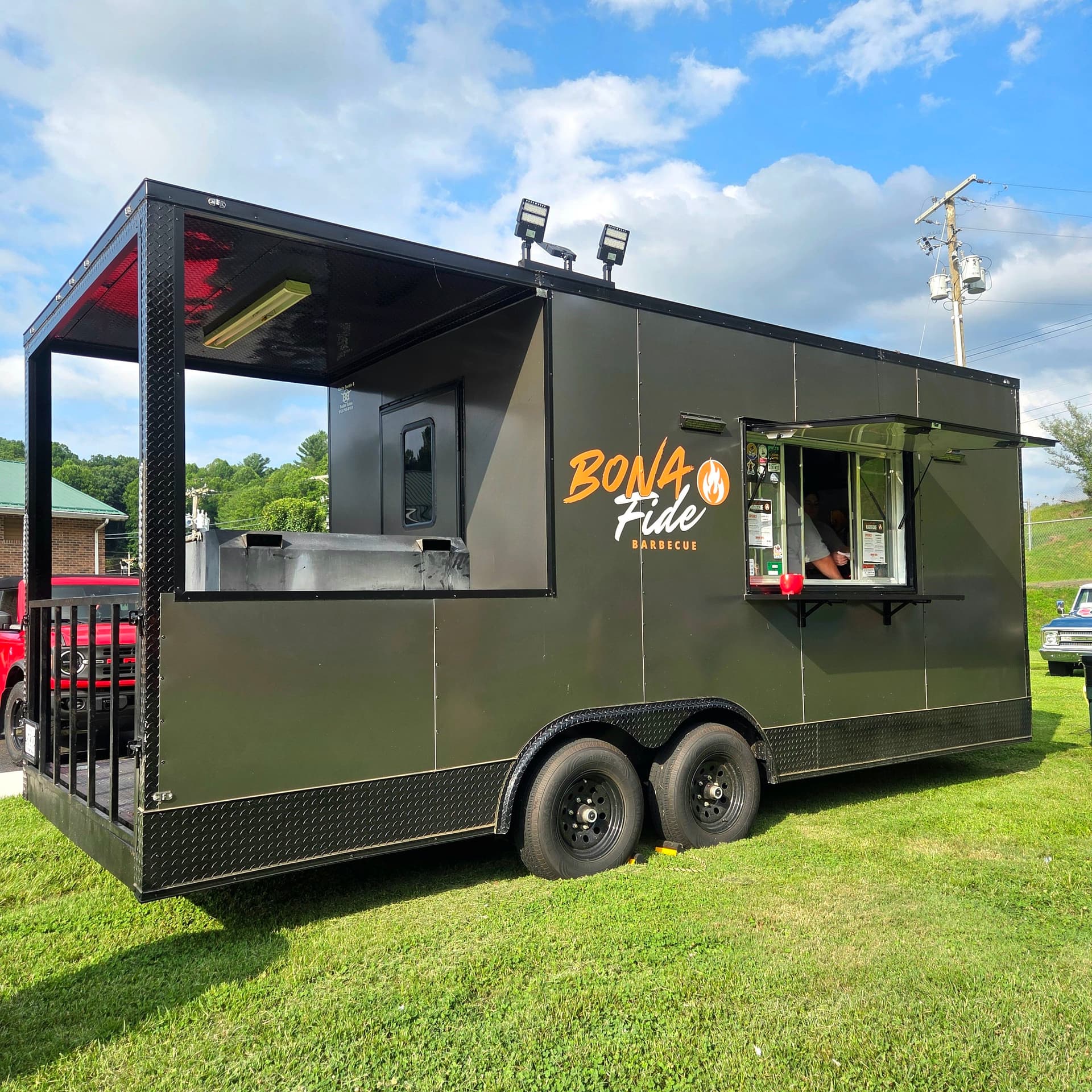 Bona Fide Barbecue's matte-black barbecue rig, front three-quarter view, serving window open